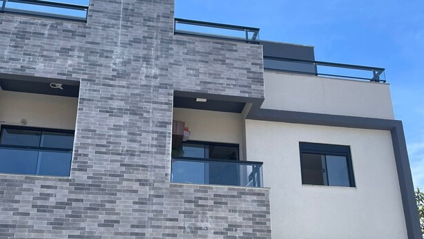 A modern two-story building with a prominent brick facade and large windows. - Apartment - Jewel Ingleses Santinho 5 minutes from the beach (Florianópolis)