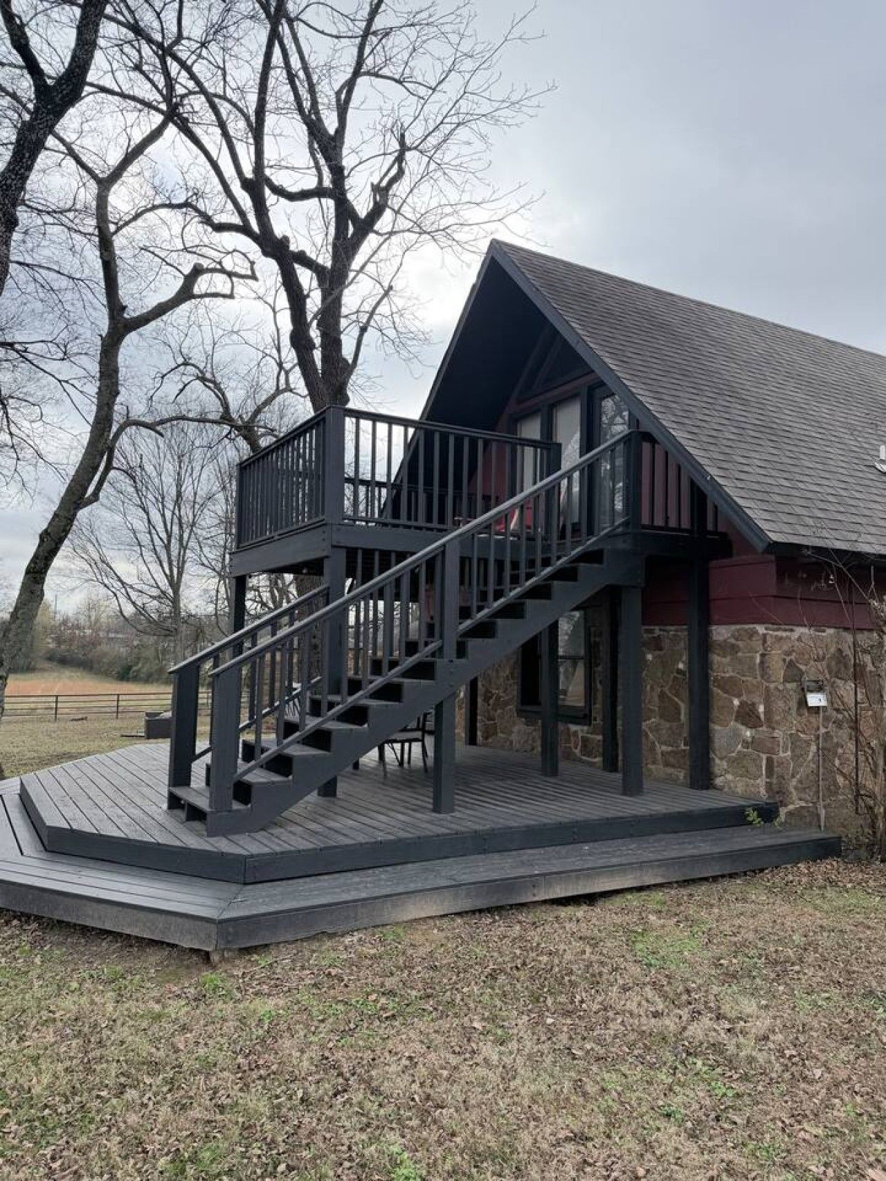 A two-story building with a wooden deck and a staircase leading to a balcony.