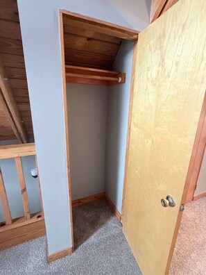 A corner room with a wooden ceiling, a door, and a carpeted floor.