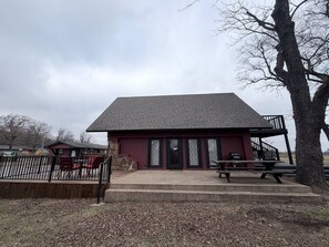 A small building with a flat roof, a front porch, and a picnic table.