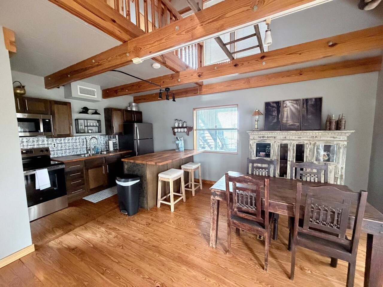 A kitchen with wooden beams, a bar area, and a dining set.