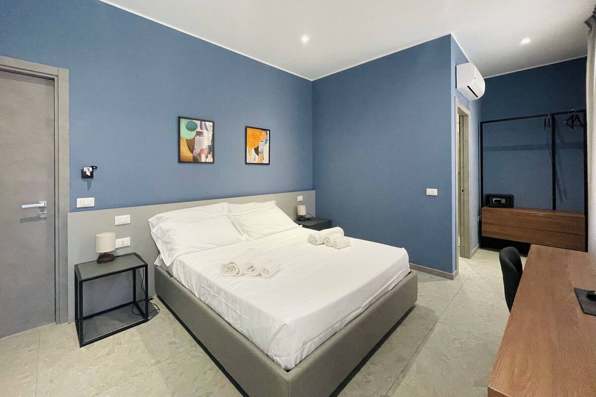 A modern bedroom with a bed, bedside tables, and artwork on the walls.