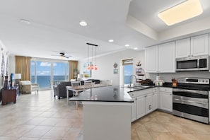A modern kitchen with white cabinets, a large island, and a view to the outside. - San Carlos 1509| Beach Front (Gulf Shores)
