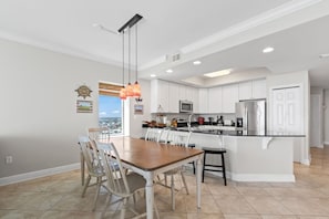 A modern kitchen with white cabinets, a central island, and pendant lighting. - San Carlos 1509| Beach Front (Gulf Shores)