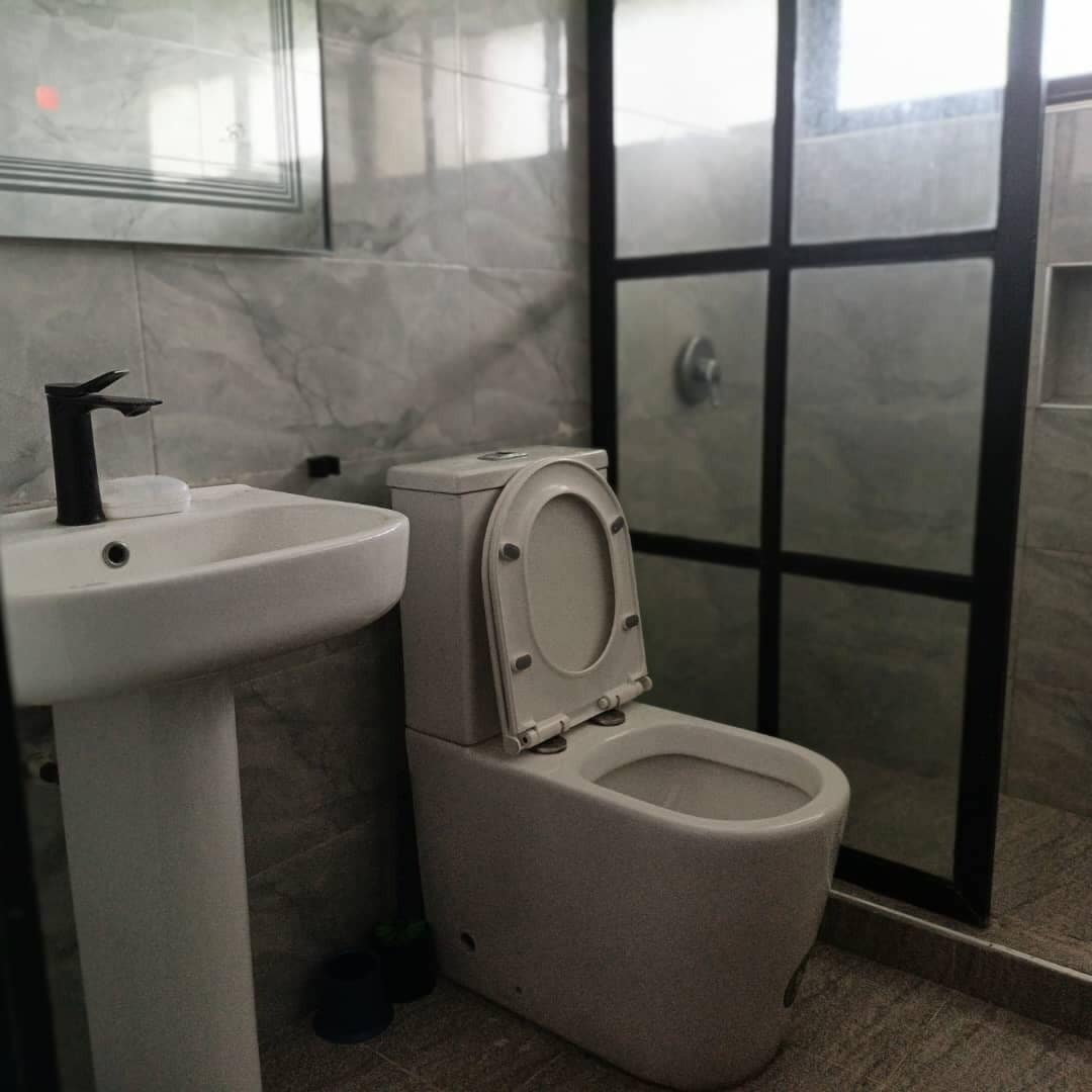 Un bagno con lavandino, wc e cabina doccia in vetro.