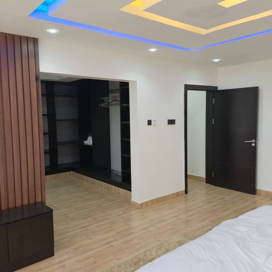 Ein Schlafzimmer mit Bett, Holzboden, Kleiderschrank und Tür.