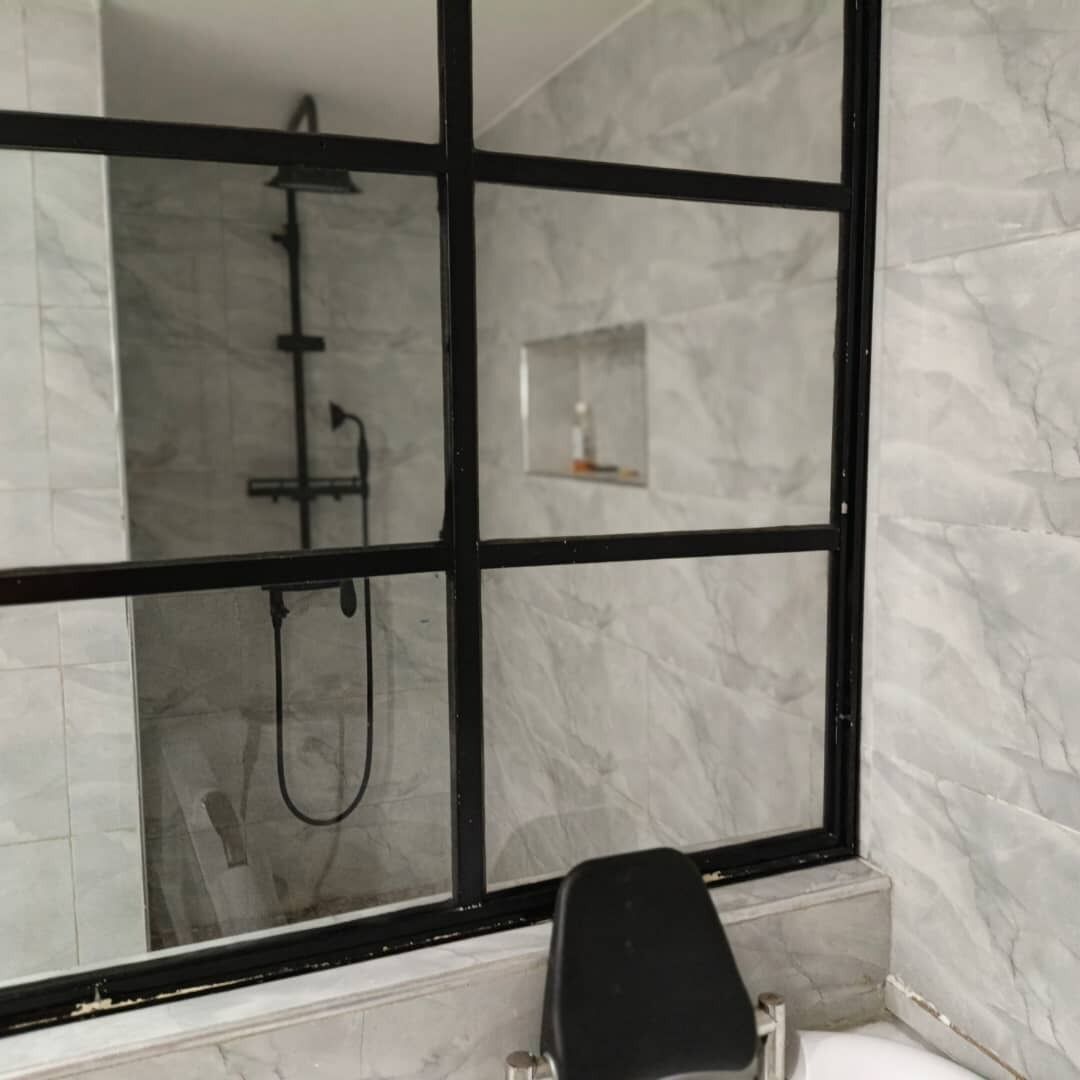 Un bagno con un grande specchio, una doccia e una parete in marmo.
