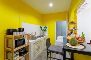 A compact kitchen with a microwave, coffee maker, and various utensils on a shelf. - Baan Singharaj Old City (Chiang Mai)