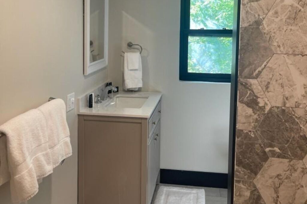 A bathroom with a sink, mirror, and a window.