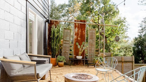 An outdoor patio with a fire pit, seating, and potted plants.