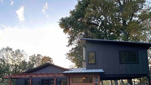 A two-story cabin with a covered porch and a car parked in front.