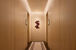 Un pasillo con paredes de madera, alfombra estampada y una lámpara fijada a la pared.