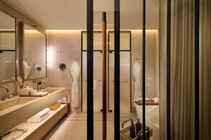 Un baño moderno con un espejo grande, dos lavamanos, una bañera y un box de ducha de vidrio.