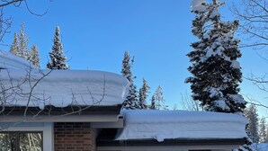 Uma casa de dois andares com fachada de tijolos, janelas grandes e telhado coberto de neve.