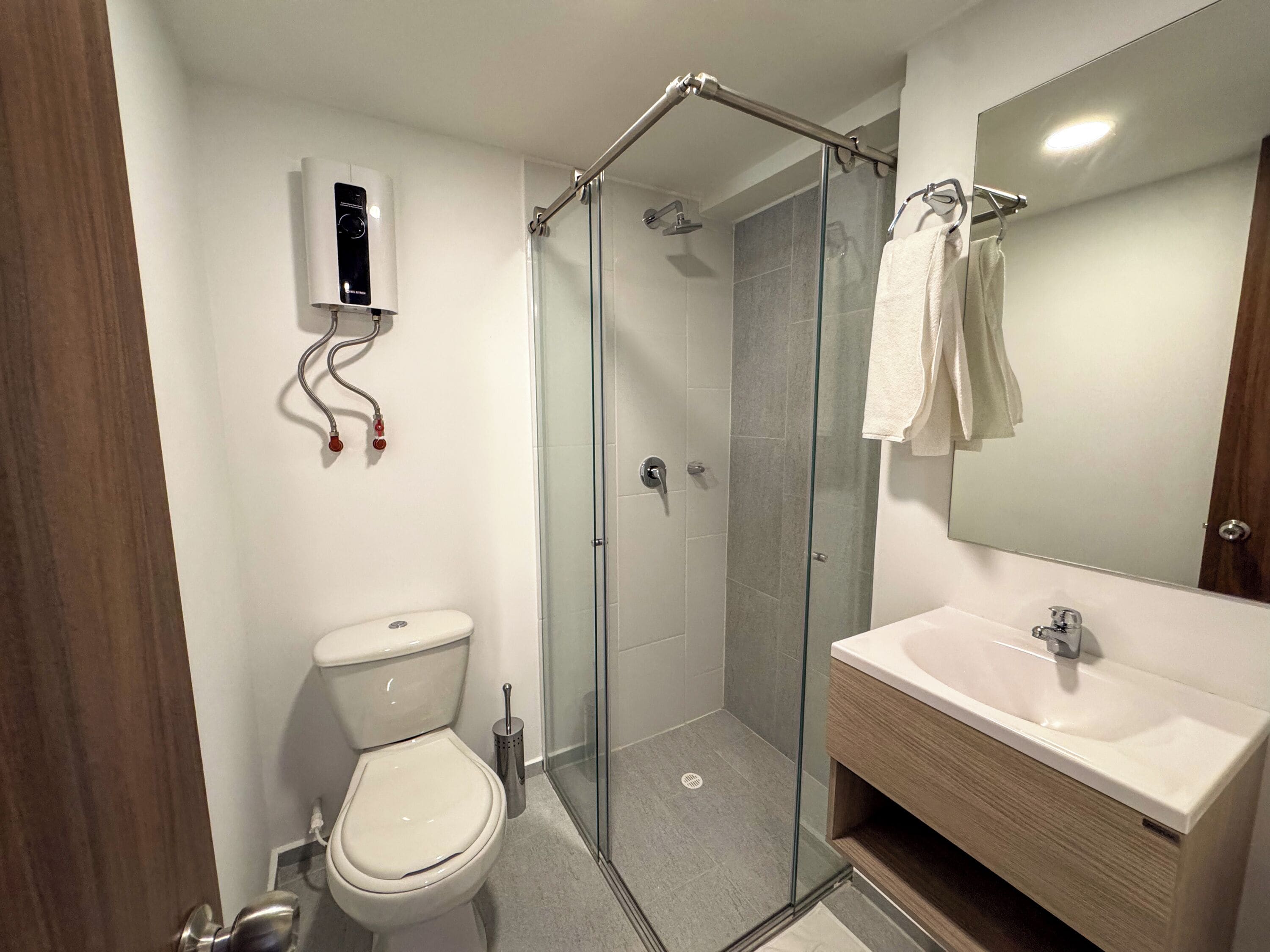 Un baño moderno con ducha envuelta en vidrio, inodoro y tocador con espejo.