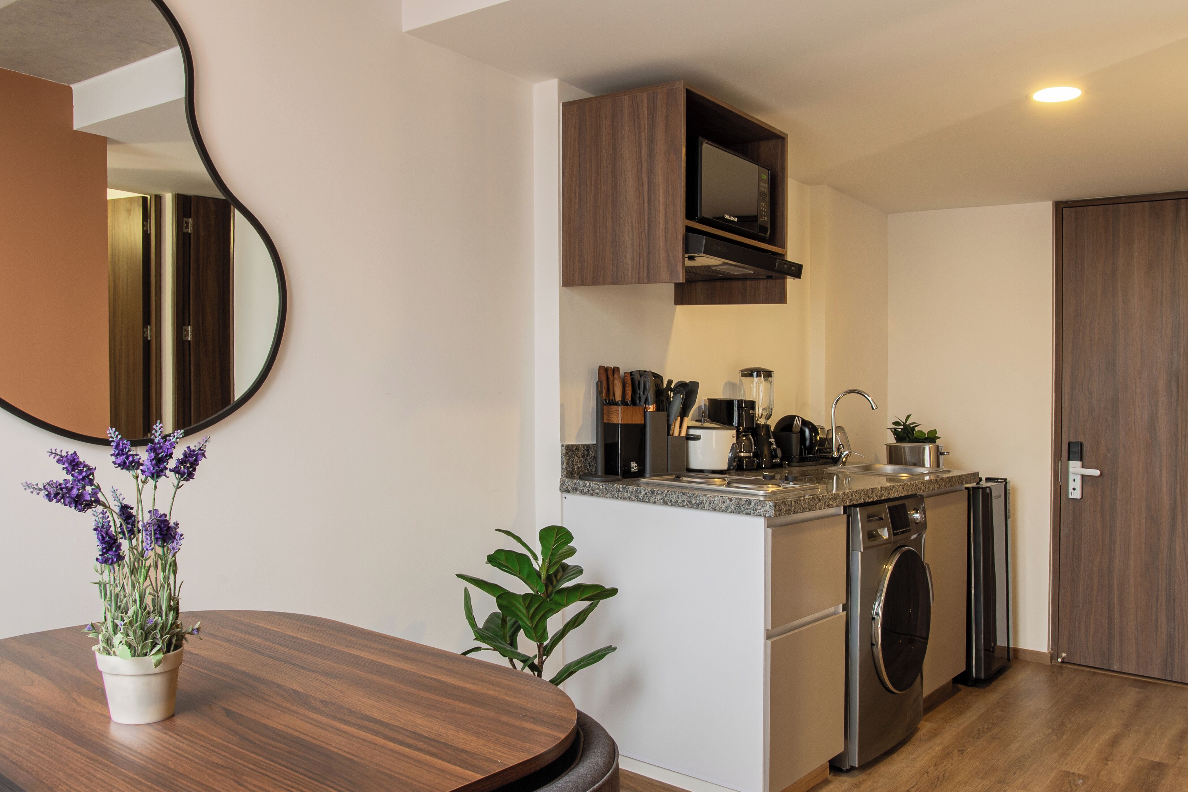 Una cocina compacta equipada con microondas, pileta y electrodomésticos de acero inoxidable.