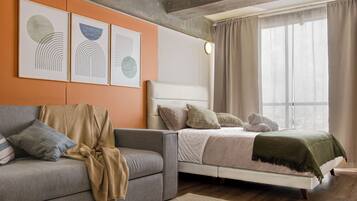 Een moderne slaapkamer met een grijze bank, een wit bed en kunst aan de muur.