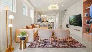 Ein modernes Wohnzimmer mit einer Couch, zwei Sesseln, einem Couchtisch, einer Stehlampe und einem Fernseher.