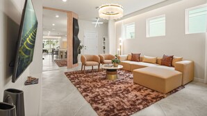 Ein modernes Wohnzimmer mit Ecksofa, Sesseln, Couchtisch und Flachbildfernseher.