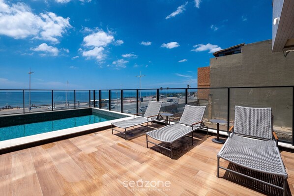 A rooftop pool area with lounge chairs and a view of the beach. - Studios in Building w/ Pool and Gym - Jdns (Salvador)