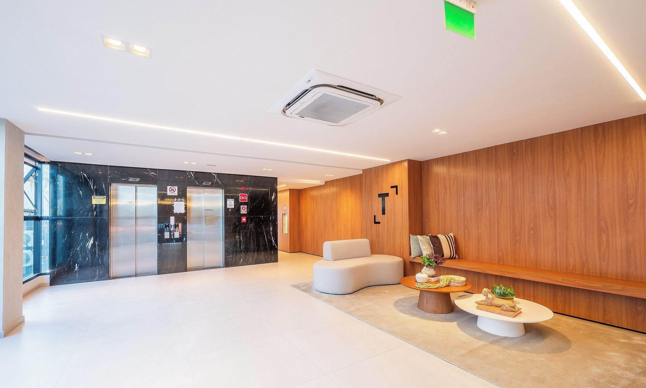A modern lobby with a reception desk, seating area, and elevators.