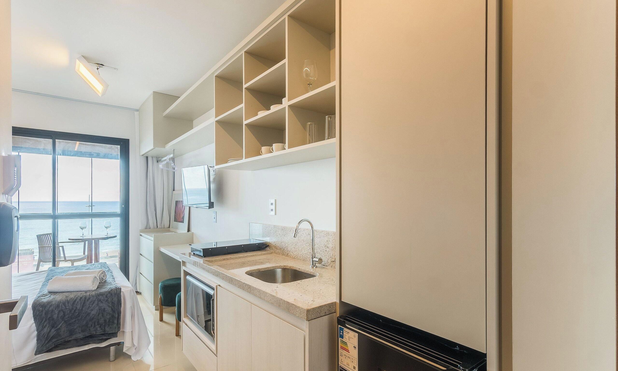 Cocina compacta con lavamanos, encimera y armarios superiores.