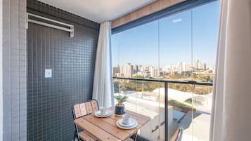 A balcony with a table, chairs, and a potted plant.