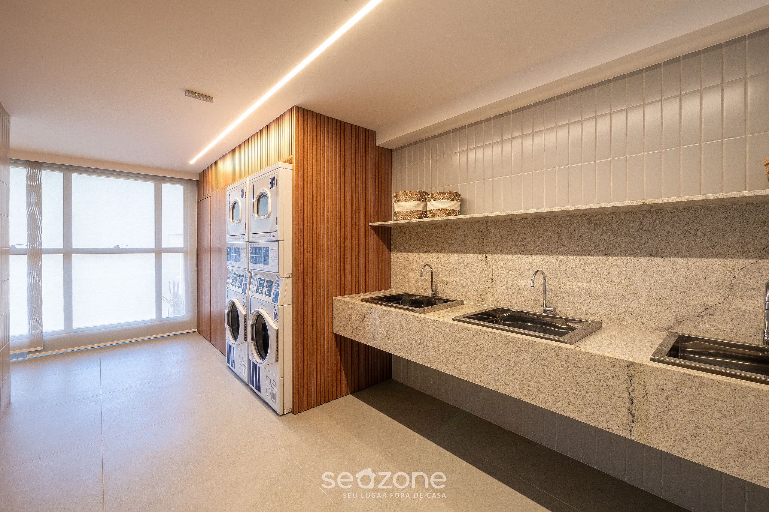 A modern kitchen with built-in appliances, a granite countertop, and a large window.