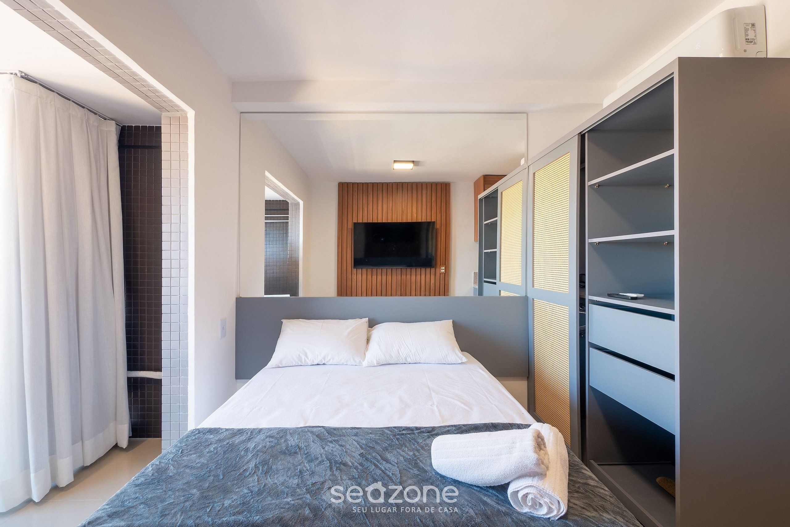 A modern hotel room with a bed, a wardrobe, and a television.