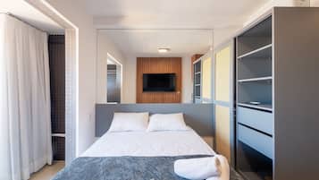 A modern hotel room with a bed, a wardrobe, and a television.