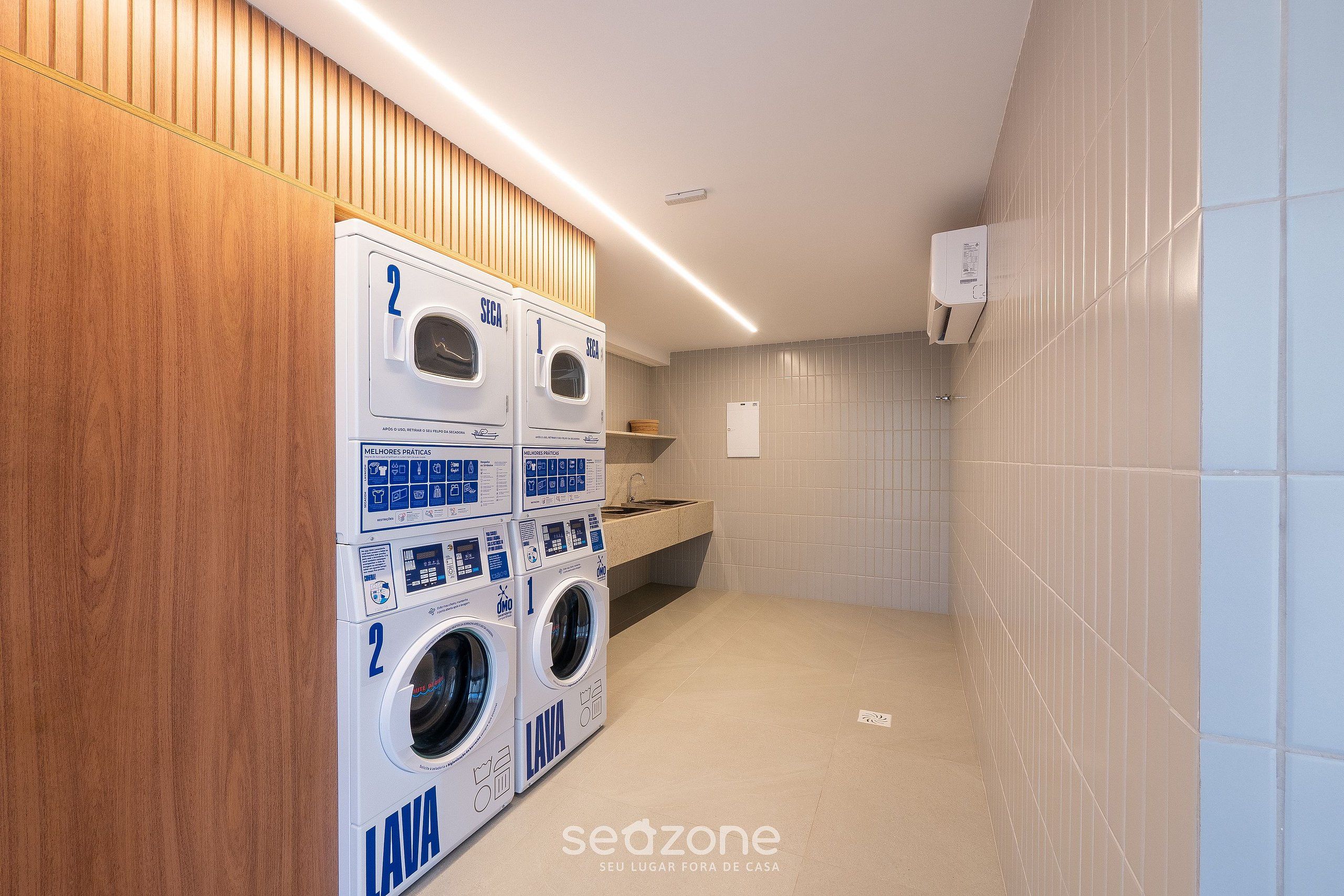 A laundry area with two front-loading washing machines, a sink, and a wooden panel wall.