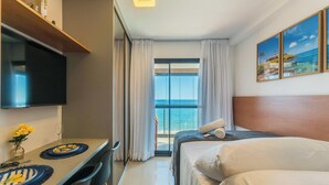 Une chambre d’hôtel comprenant un lit, un bureau avec un téléviseur à écran plat, un coin repas et une vue sur l’océan.