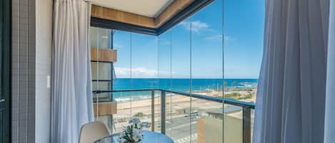 A balcony with a glass table, a chair, and a potted plant.
