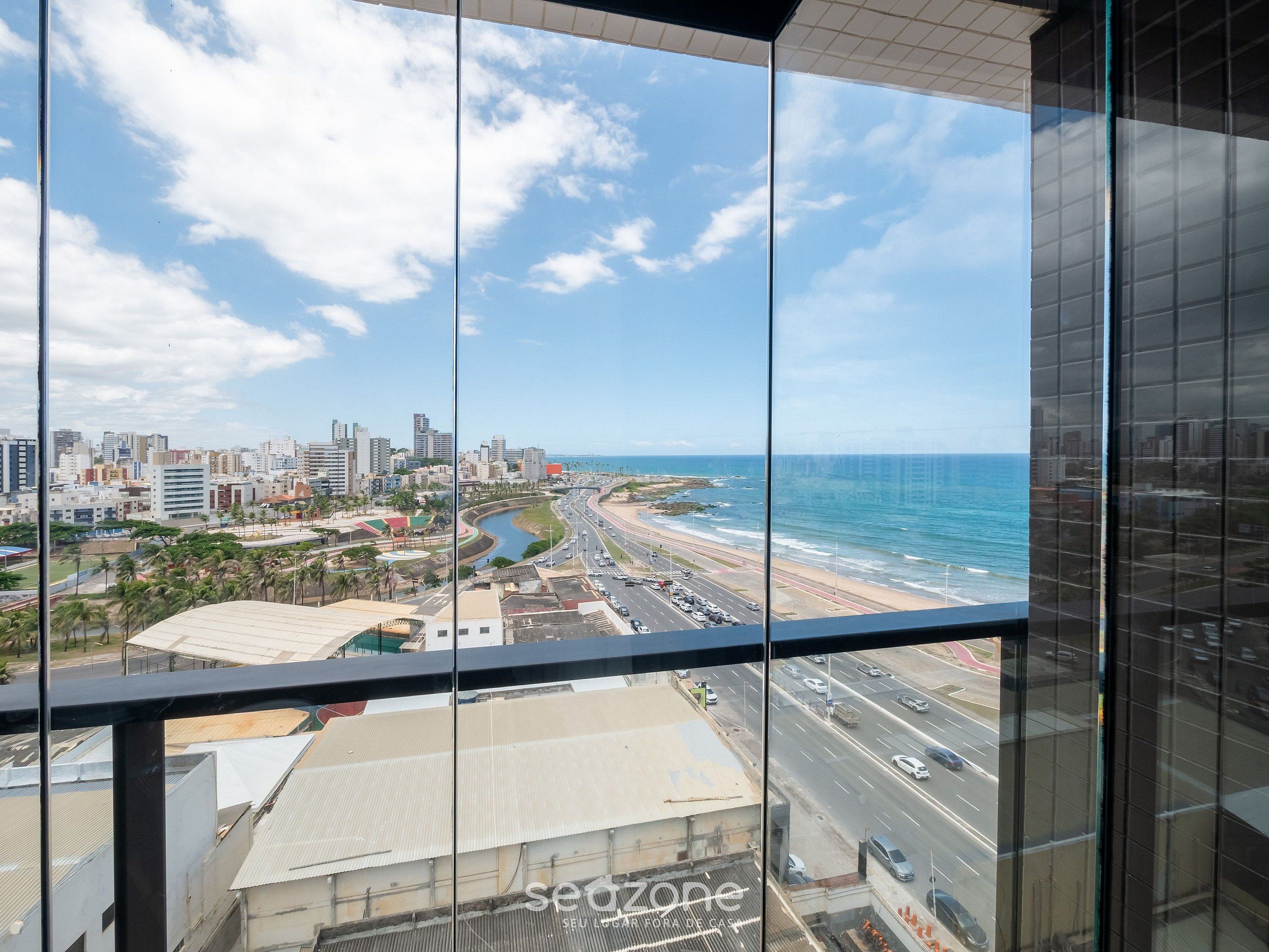 A high-rise building with a view of a coastal cityscape, including a beach and a river.