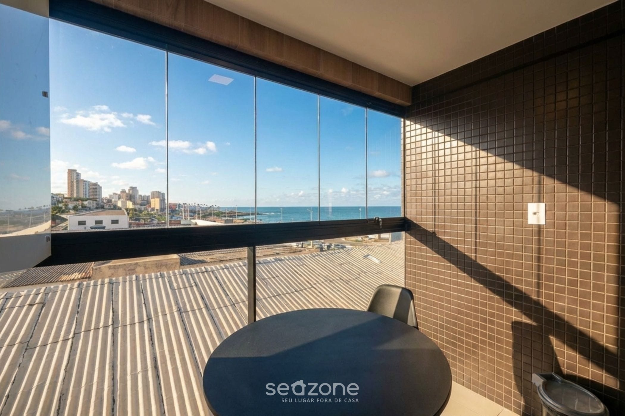 Una habitación moderna con un ventanal grande que da a una vista de la ciudad y el mar.