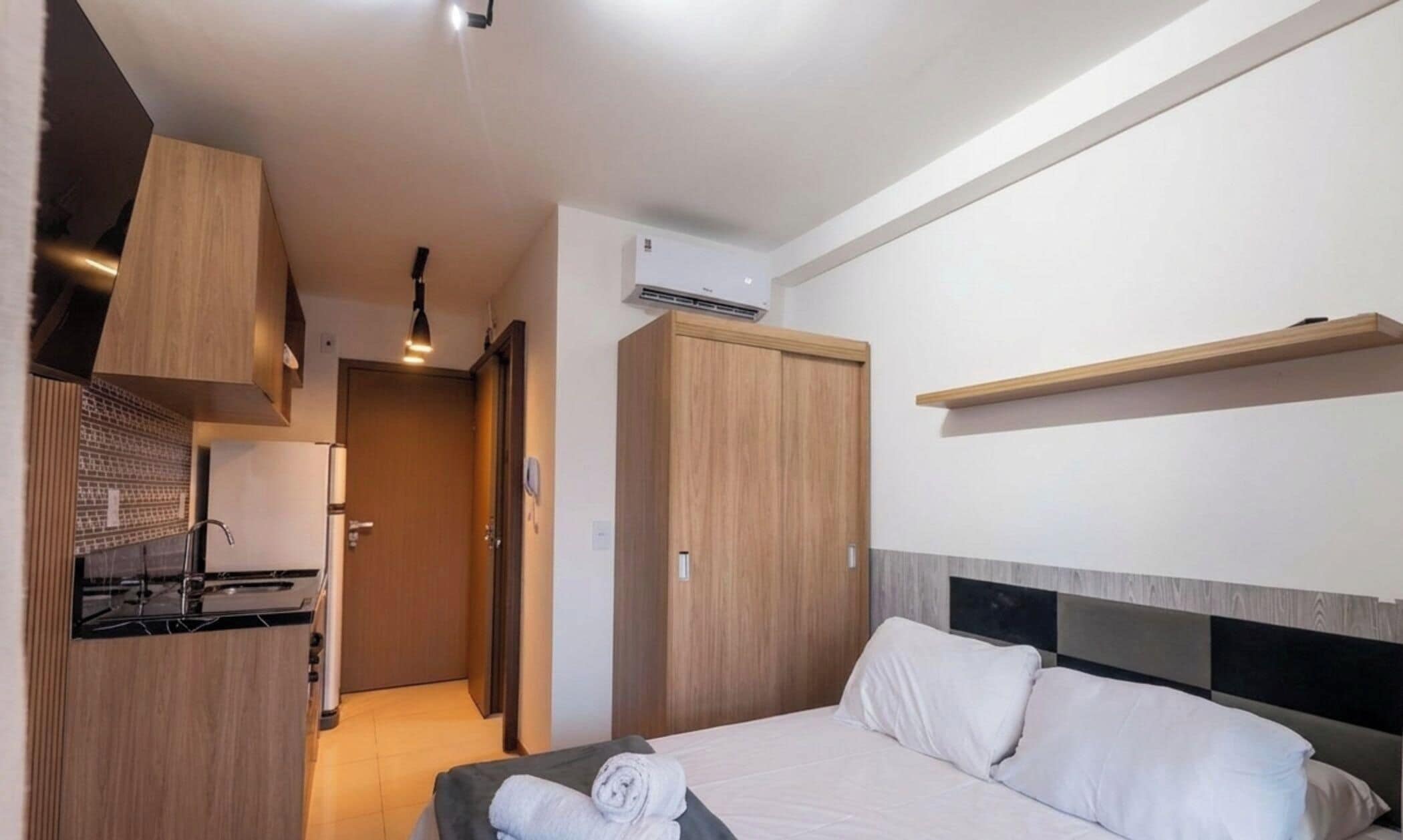 Een hotelkamer met een bed, een inbouwkast, een kitchenette en een badkamer.