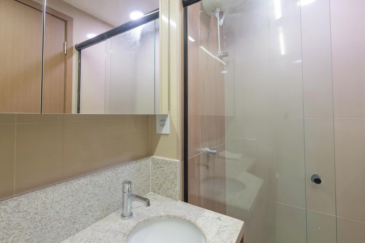 A bathroom with a sink, mirror, and shower enclosure.