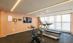 A gym with exercise equipment, a TV, and large windows. - Studios in Building w/ Pool and Gym - Jdns (Salvador)