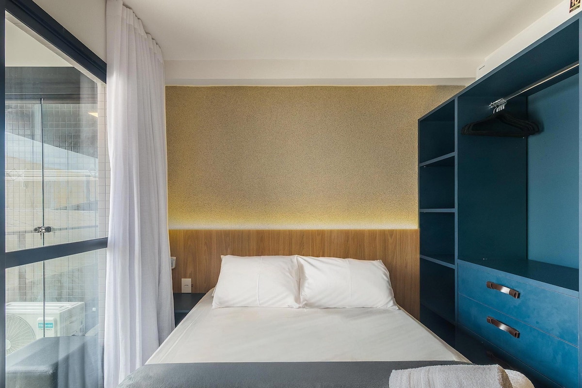 A hotel room with a bed, a wardrobe, and a view through a window.