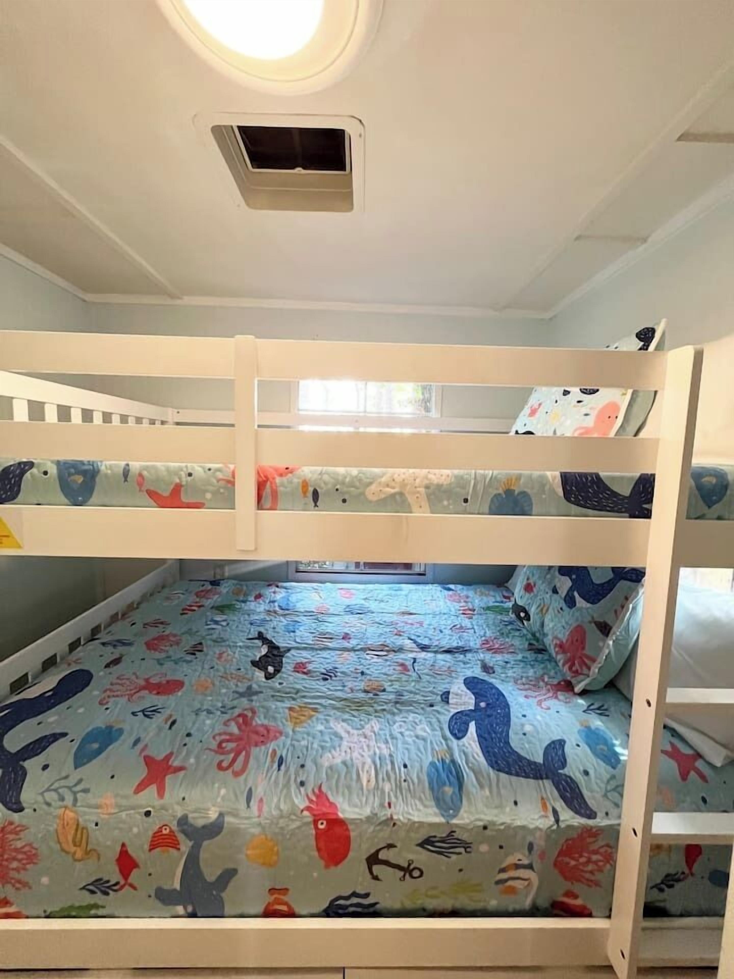 Una cama litera con ropa de cama de temática marina y colores vivos.