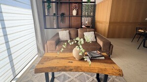 A modern living room with a brown sofa, a wooden coffee table, and a bookshelf with decorative items.
