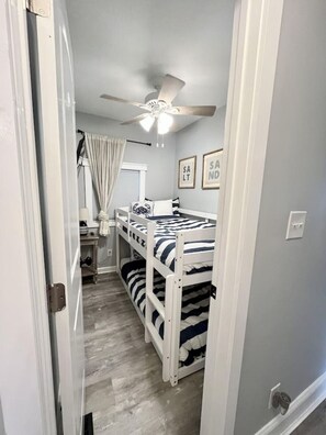 A narrow room with a bunk bed, a ceiling fan, and a window with curtains. - P35 The Sand Bucket Retreat (Myrtle Beach)