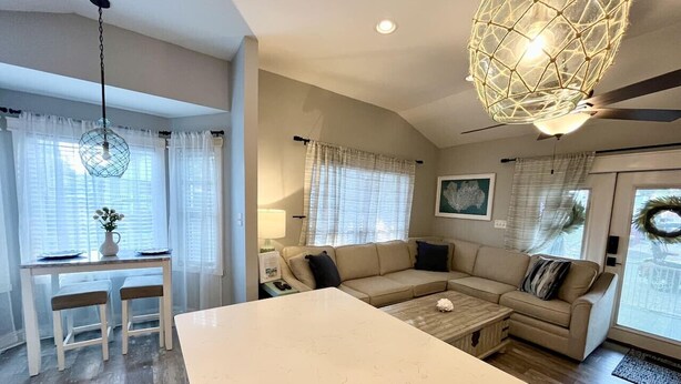Ein modernes Wohnzimmer mit einem großen weißen Tisch, einem beige farbenen Sofa und einem Deckenventilator.