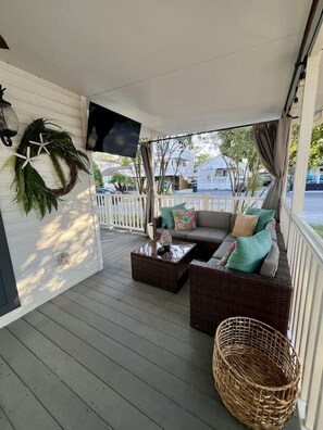 A covered porch with a sofa, a coffee table, and a wicker basket. - P35 The Sand Bucket Retreat (Myrtle Beach)
