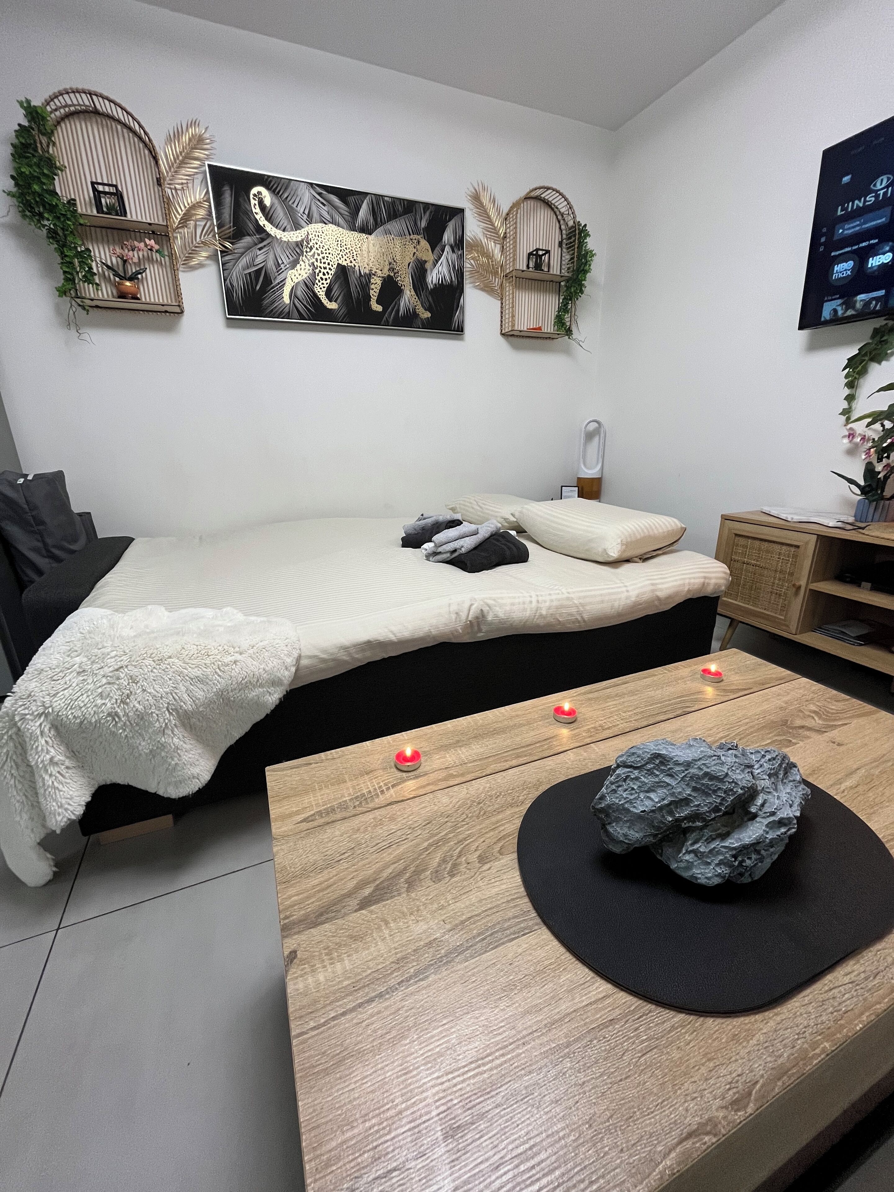 A modern bedroom with a bed, bedside table, and a TV mounted on the wall.