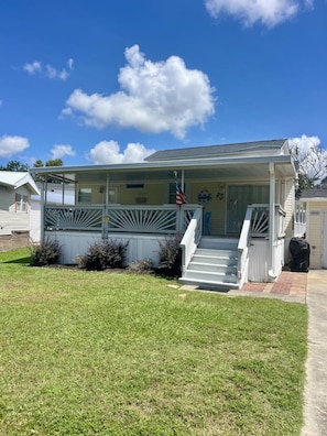 A single-story house with a covered porch, a front yard, and an American flag. - 6010 Almost Heaven By The Sea (Myrtle Beach)