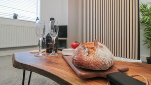 A wooden table with a loaf of bread, a bottle of wine, and two glasses. - Islas Sea Forge (Saltburn-by-the-Sea)