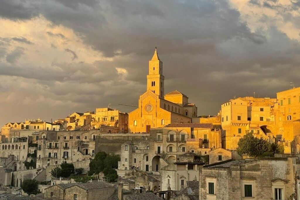 A historic town with a prominent church featuring a tall bell tower, surrounded by densely packed buildings with traditional architecture.