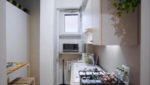 Una cocina compacta con microondas, pileta y una mesita con tabla.
