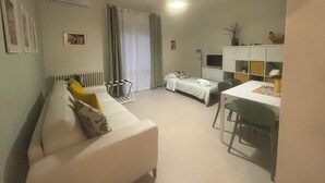 Un espacio habitable compacto con sofá, una mesa de comedor con sillas, una cama pequeña y un radiador.